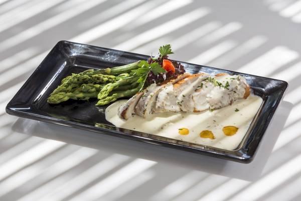 Gebratenes Huhn mit Spargel und Sauce auf schwarzem Teller