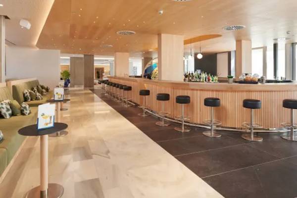 Innenansicht der Bar im Hipotels Mediterraneo Hotel mit Barhockern und grünen Sofas.