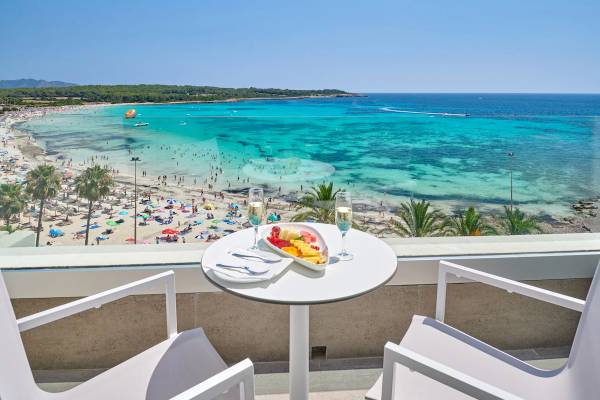 Blick vom Balkon des Hipotels Mediterraneo auf einen Strand mit vielen Menschen und kristallklarem Wasser.