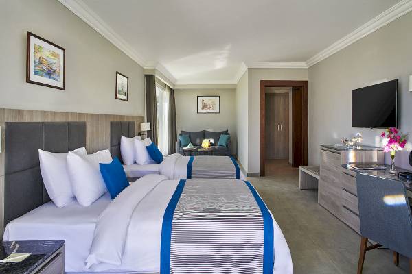 Schlafzimmer im Maritim Jolie Ville Resort & Casino Sharm El Sheikh mit drei Betten, Fernseher und Schreibtisch.