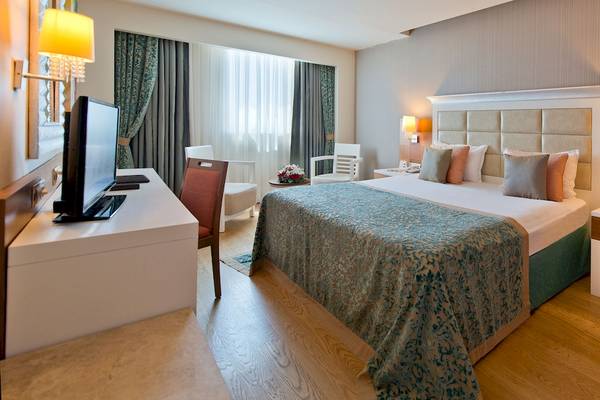 Hotelzimmer des Sentido Kamelya Selin mit großem Bett, Fernseher, Schreibtisch und Stühlen.