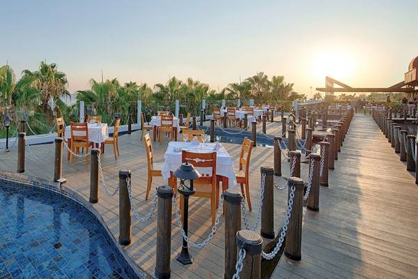 Terrasse des Sentido Kamelya Selin Hotels mit Swimmingpool und Tischen bei Sonnenuntergang