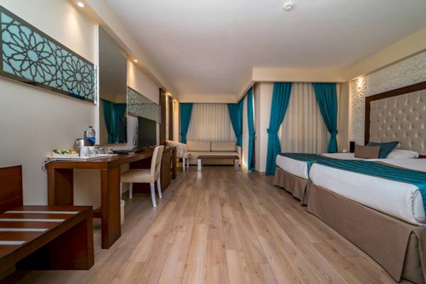 Innenansicht eines Hotelzimmers im Sentido Kamelya Selin mit zwei Betten, Schreibtisch und Fernseher.