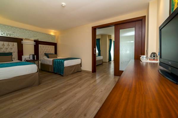 Doppelzimmer im Sentido Kamelya Selin Hotel mit zwei Betten, Fernseher und Schreibtisch.