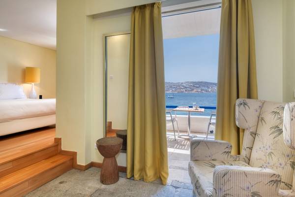 Zimmer im Mykonos Theoxenia Boutique Hotel mit Blick auf das Meer von einem Balkon.