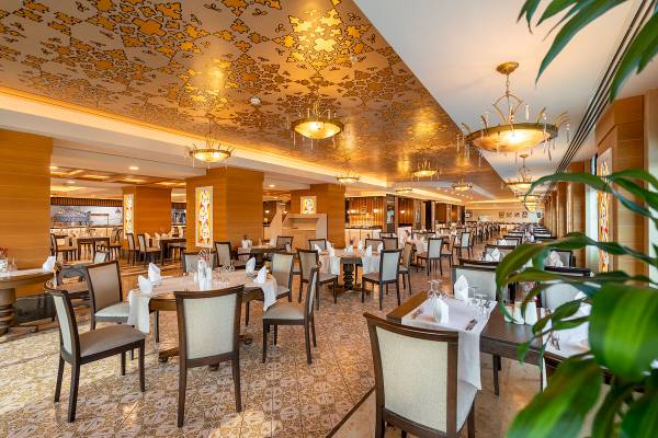 Innenansicht des Restaurants im Sentido Kamelya Selin Hotel mit gedeckten Tischen und goldenen Deckenverzierungen.