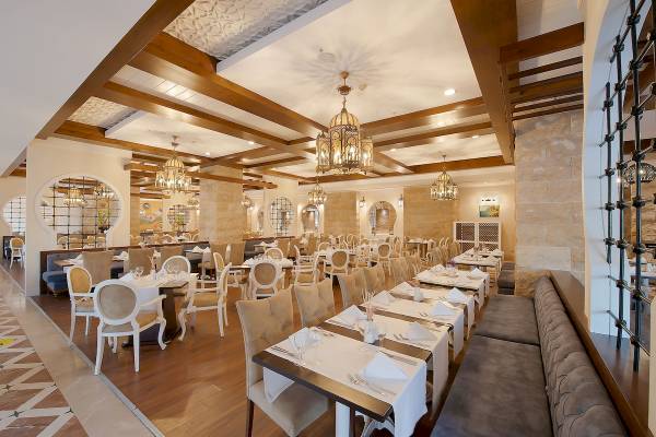 Innenansicht des Restaurants im Sentido Kamelya Fulya Hotel mit Tisch und Stühlen, Holzboden und Steinwänden.
