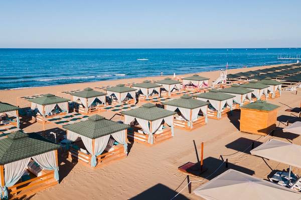 Eine Reihe von Sonnenhuten auf einem sandigen Strand des Sentido Kamelya Fulya Hotels