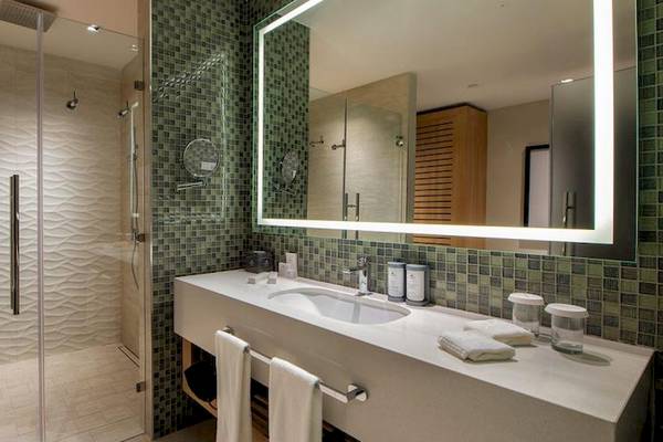 Badezimmer im Lopesan Costa Bavaro Resort Spa & Casino mit Glasdusche, Waschbecken und Spiegel.