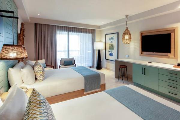 Doppelzimmer im Lopesan Costa Bavaro Resort mit zwei Betten, Fernseher, Schreibtisch und Schlafbereich.
