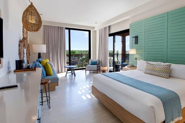 Suite-Innenansicht im Lopesan Costa Bavaro Resort Spa & Casino mit Bett, Balkon, Fernseher und Möbeln.