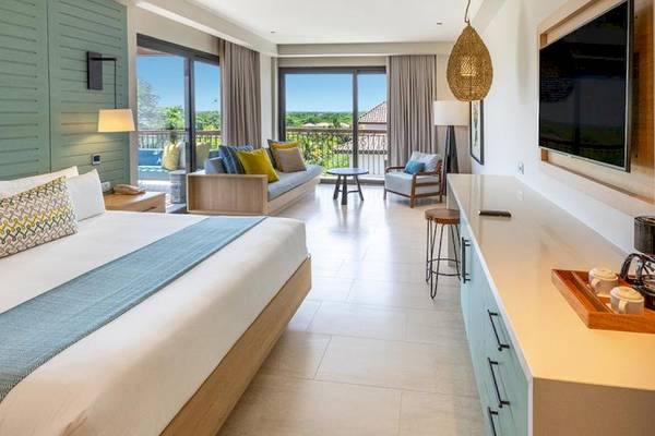 Ein elegantes Hotelzimmer im Lopesan Costa Bavaro Resort mit Blick auf die Terrasse und einem großen Bett.