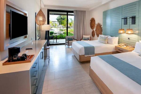 Hotelzimmer im Lopesan Costa Bavaro Resort Spa & Casino mit zwei Betten, Fernseher und Aussicht auf Garten.