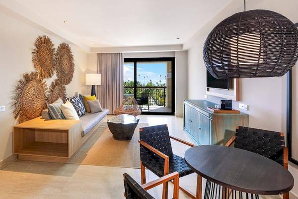 Innenansicht einer Hotelsuite mit Balkon, Wohnzimmer, Bett, Tisch und Stühlen.
