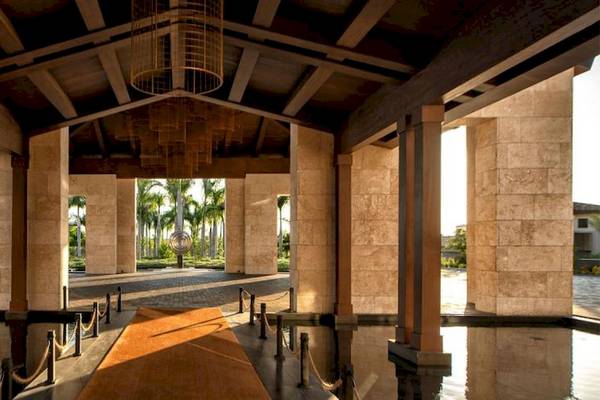 Der Eingang des Lopesan Costa Bavaro Resorts mit einem langen roten Teppich und hohen Steinsäulen.