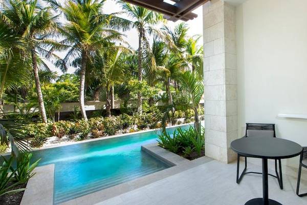 Terrasse mit Tisch und Sesseln vor einem Pool im Lopesan Costa Bavaro Resort Spa & Casino