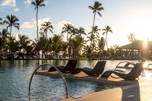 Pool des Lopesan Costa Bavaro Resorts bei Sonnenuntergang mit Palmen und Loungeliegen