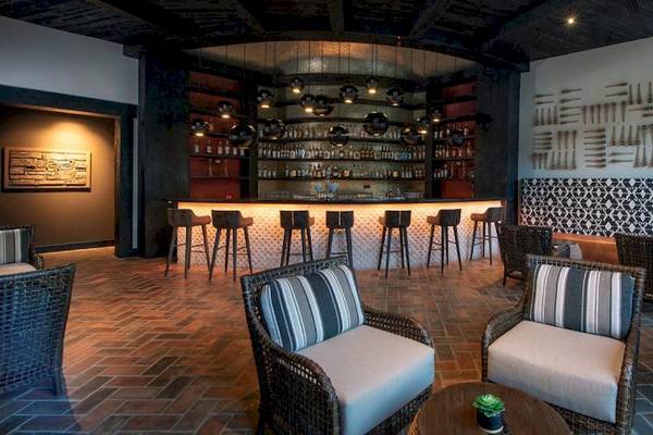Innenansicht der Bar im Lopesan Costa Bavaro Resort Spa & Casino mit Thekenhockern und Wanddekorationen.