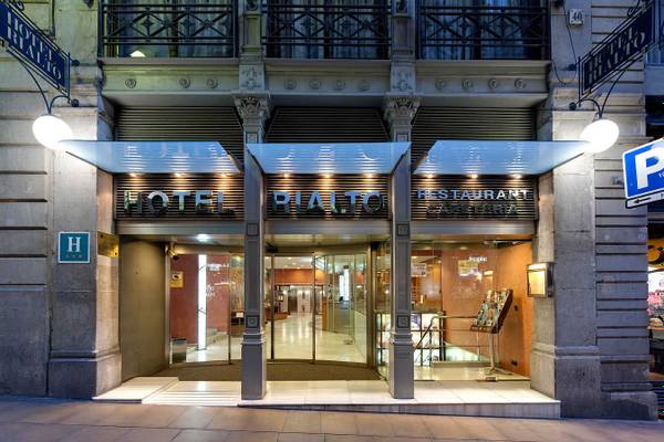 Außenansicht des Hotel Rialto mit Beleuchtung und Hotelschildern an der Fassade.