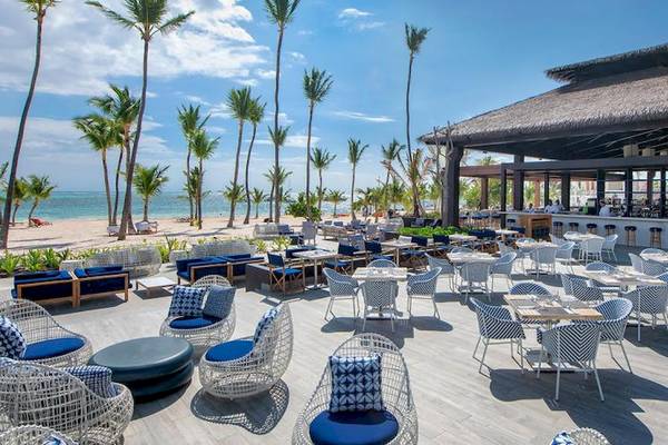 Außenterrasse des Lopesan Costa Bavaro Resorts mit vielen Tischen und Stühlen am Strand