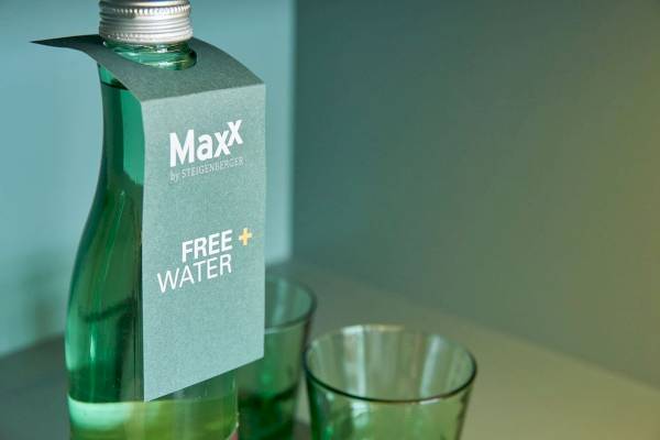 Grüne Flasche mit 'Free + Water'-Etikett und zwei grünen Gläsern