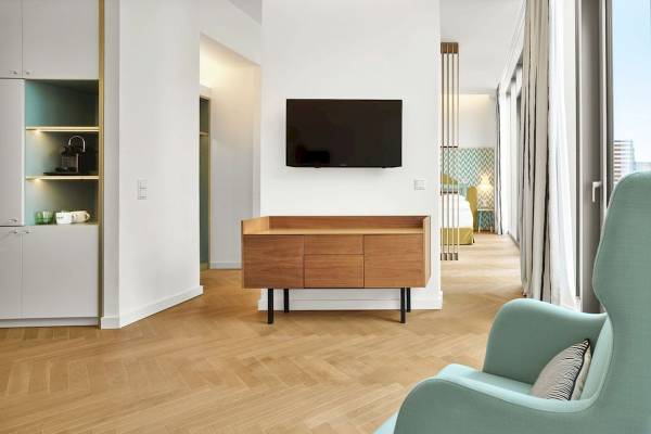 Innenansicht eines Zimmers im MAXX by Steigenberger Vienna Hotel mit Holzboden, weißen Wänden und einem Fernseher an der Wand.