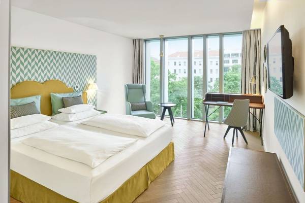 Doppelbett Zimmer im MAXX by Steigenberger Vienna mit zeitgenössischem Design und Blick auf die Stadt.