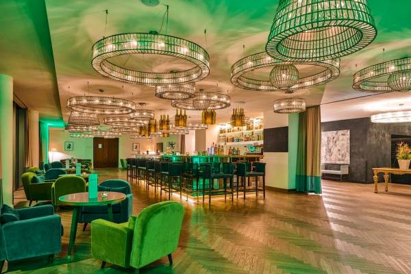 Interieur der Bar im MAXX by Steigenberger Vienna mit grünen Möbeln und Kronleuchtern.