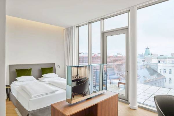 Schlafzimmer im MAXX by Steigenberger Vienna mit Doppelbett, Balkon und Stadtblick.