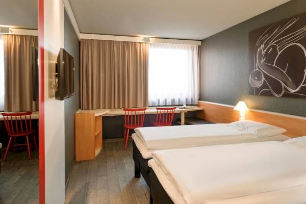 Doppelzimmer im Ibis Wien Mariahilf mit zwei Betten, Schreibtisch und Fernseher.