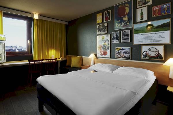 Schlafzimmer im Ibis Wien Mariahilf Hotel mit Bett, Nachttischen und Schreibtisch