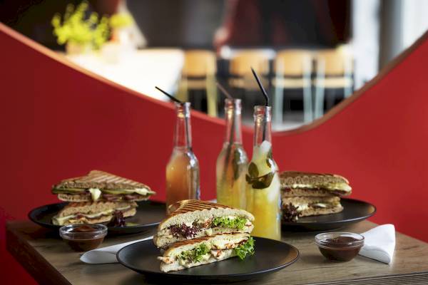 Sandwiches, Getränke und Beilagen auf einem Tisch im Ibis Wien Mariahilf