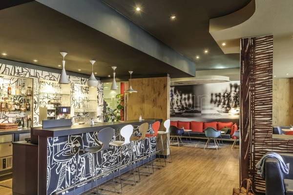 Innenansicht der Bar im Ibis Wien Mariahilf Hotel mit Barhockern, Tisch und moderner Einrichtung.