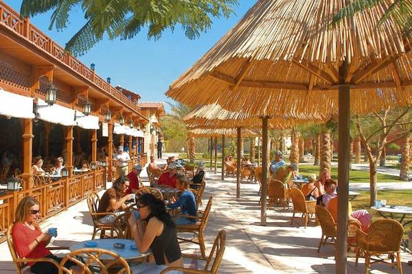 Gäste sitzen auf der Terrasse des Siva Grand Beach Hotels unter Strohdächern.