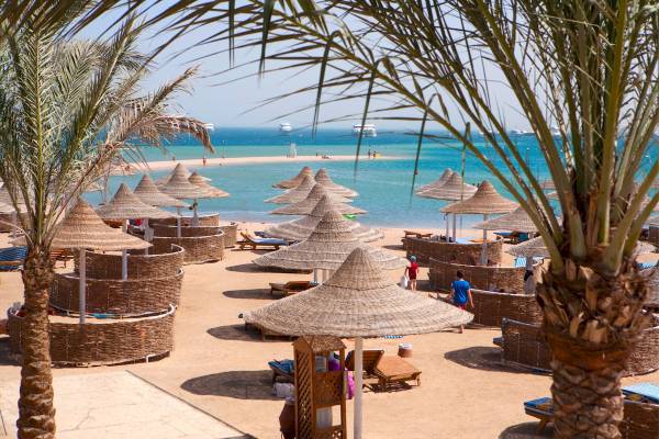 Strandszene im Siva Grand Beach Hotel mit Palmen, Sonnenschirmen und Loungestühlen