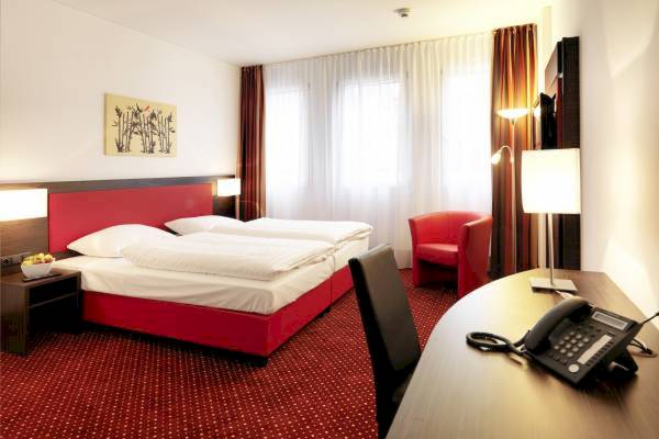 Hotelzimmer im Best Western Plus Amedia Wien mit rotem Bett und Schreibtisch.