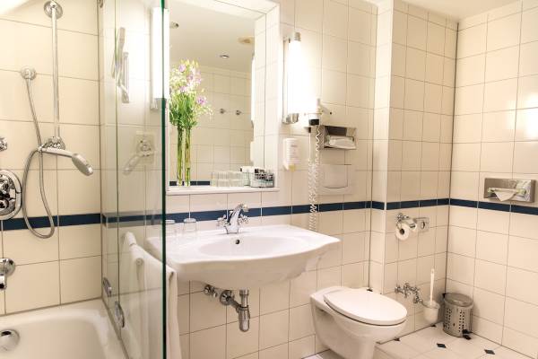 Badezimmer im Mercure Grand Hotel Biedermeier mit Badewanne, Dusche, Toilette und Waschbecken.