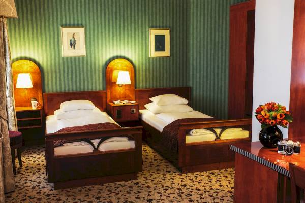 Doppelzimmer im Mercure Grand Hotel Biedermeier mit zwei Betten, Nachttischen und Lampen.