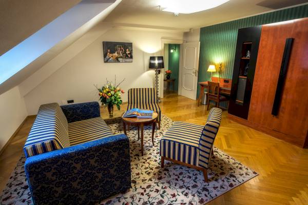 Hotelzimmer im Mercure Grand Hotel Biedermeier mit Sofa, Tisch, Stühlen und Dekor.