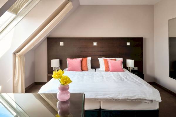 Doppelbett-Zimmer im Flemings Hotel Wien-Stadthalle mit weißem Bettlaken und bunten Kissen.
