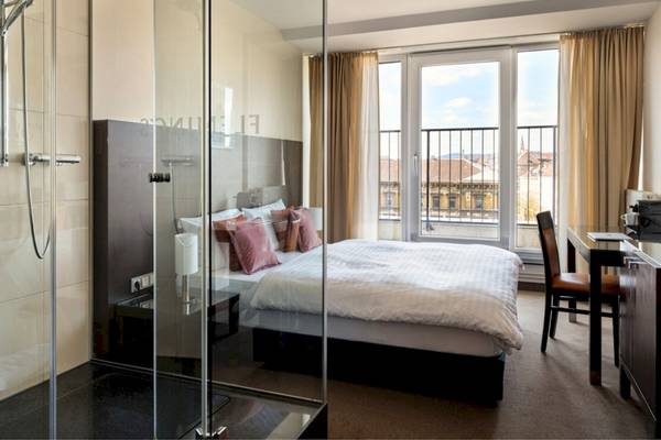 Innenansicht eines modernen Hotelzimmers mit Bett, Schreibtisch und Fenstern, Flemings Hotel Wien-Stadthalle.