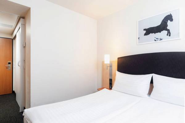 Doppelzimmer im IntercityHotel Wien mit zwei weißen Betten und einem Pferdebild an der Wand.