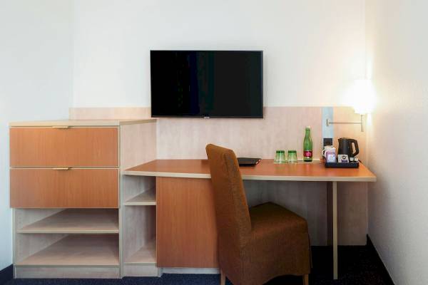 Arbeitsbereich im IntercityHotel Wien mit Schreibtisch, Fernseher und Kaffeezubehör.