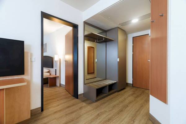 Innenansicht eines Zimmers im IntercityHotel Wien mit Fernseher, Schreibtisch und Spiegel.