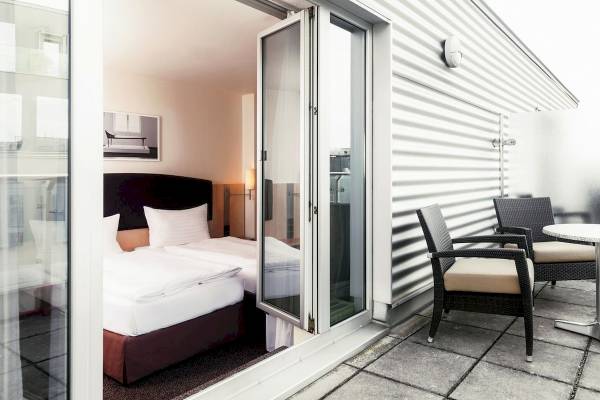 Doppelbett-Zimmer im IntercityHotel Wien mit offenem Balkon.