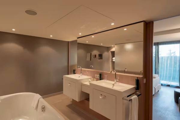 Badezimmer im DoubleTree by Hilton Vienna Schonbrunn mit Badewanne, Waschbecken und Spiegel.