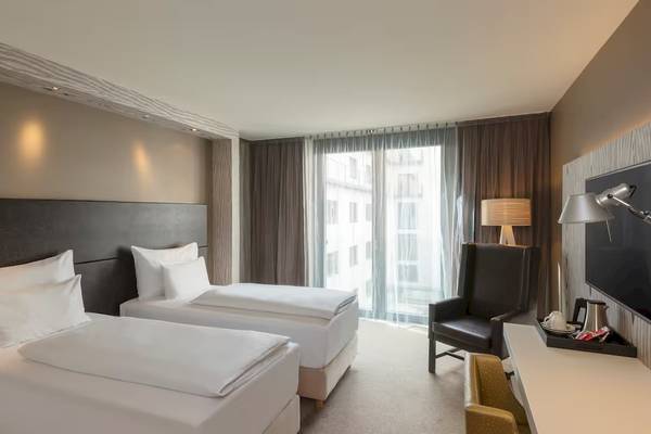 Doppelzimmer im DoubleTree by Hilton Vienna Schonbrunn mit zwei Betten, Fernseher und Arbeitsbereich.