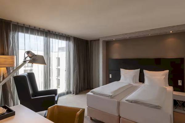 Doppelzimmer im DoubleTree by Hilton Vienna Schonbrunn mit zwei Betten und moderner Einrichtung.