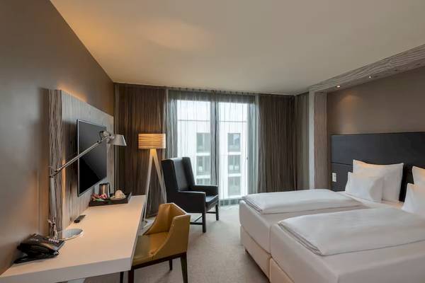 Doppelzimmer im DoubleTree by Hilton Vienna Schonbrunn mit zwei Betten, Schreibtisch und Fernseher.