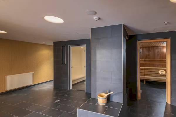 Innenansicht des Saunabereichs im DoubleTree by Hilton Vienna Schonbrunn mit schwarz gefliestem Boden und zwei offenen Saunatüren.